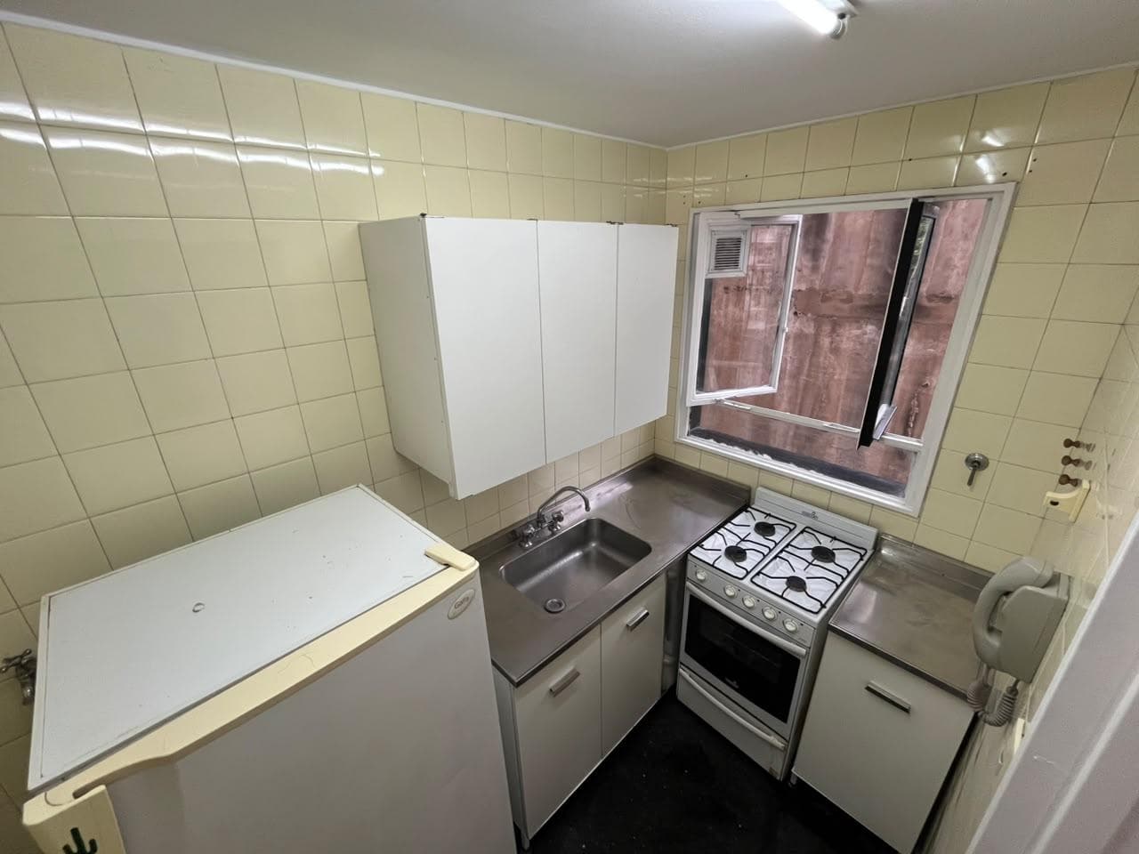 Cocina con heladera, mesada, bacha, anafe, horno y alacenas.