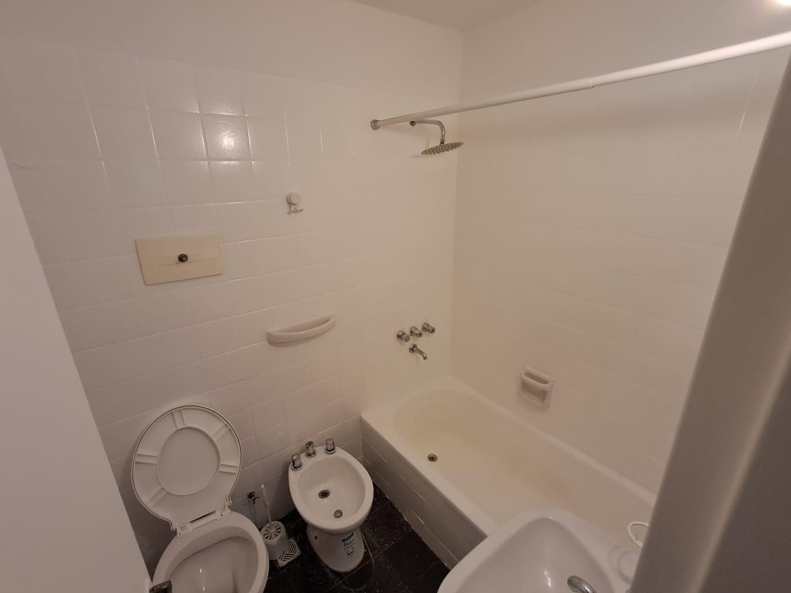 Baño completo con inodoro, bidet, lavatorio y bañera con ducha.