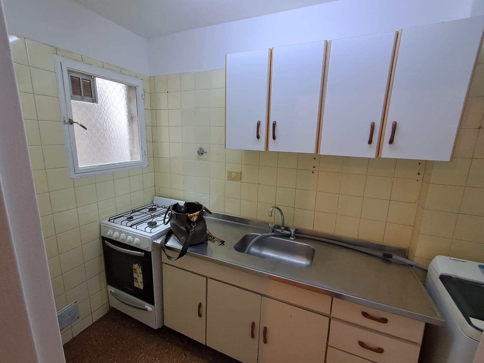 Cocina equipada con anafe, horno, bacha y alacenas superiores.