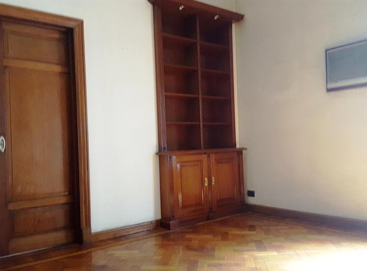 Living vacío con estantería de madera y pisos de parquet.