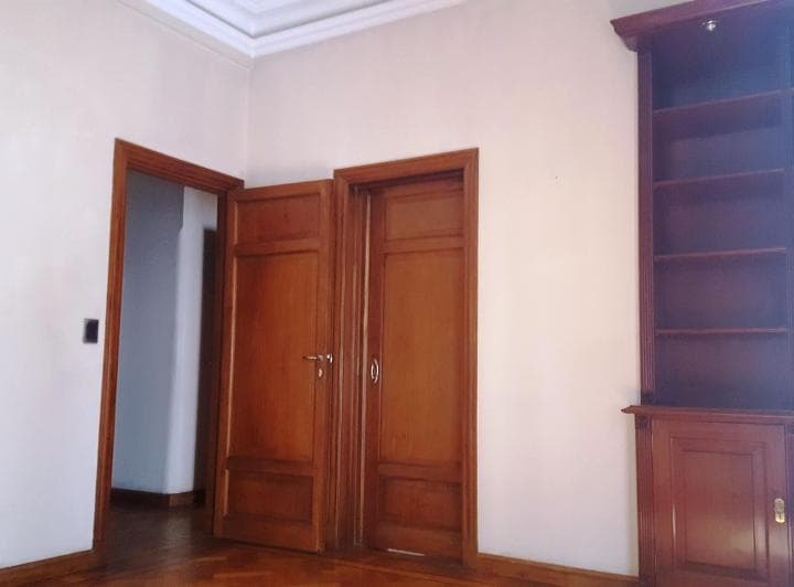 Living vacío con puertas de madera y estantería.