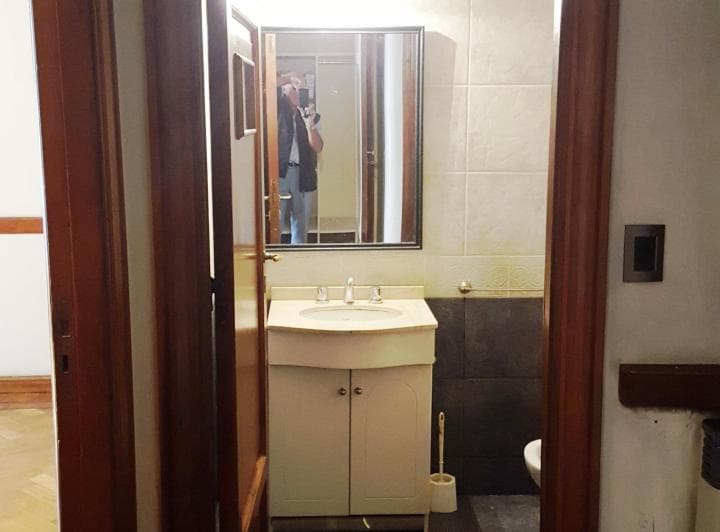 Toilette con vanitory, espejo y azulejos blancos y oscuros.
