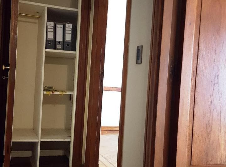 Dormitorio con placard abierto con estantes y puertas de madera.