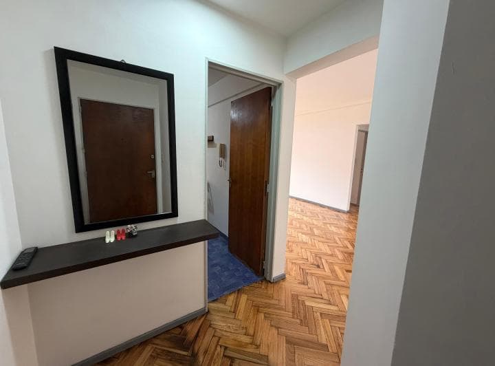 Pasillo de entrada con espejo, mesa y piso de parquet.