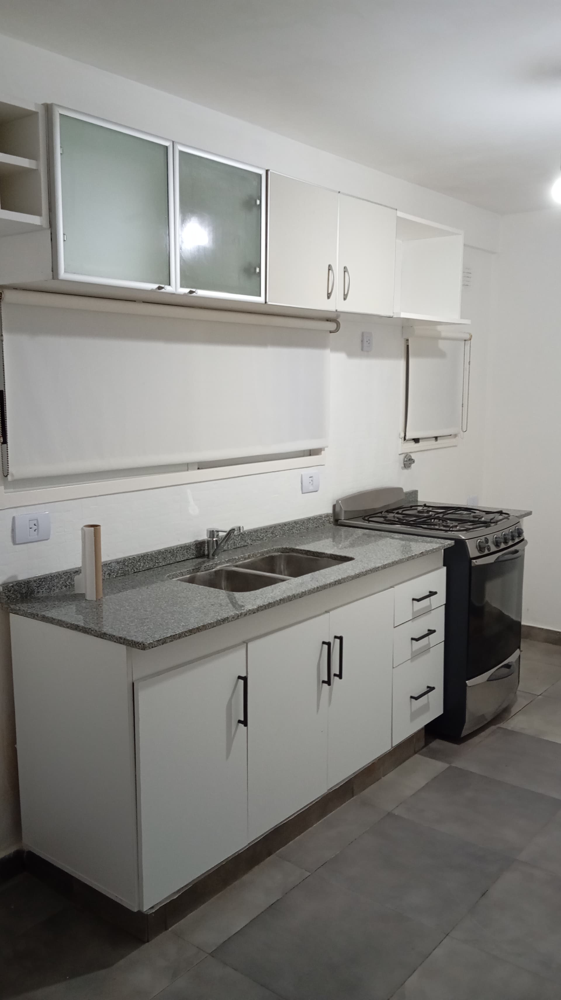 Cocina con mesada de granito, bacha doble, anafe y alacenas blancas.