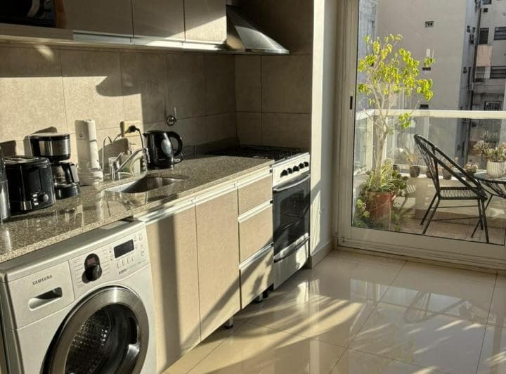 Cocina integrada con lavarropas, anafe, bacha y salida al balcón.