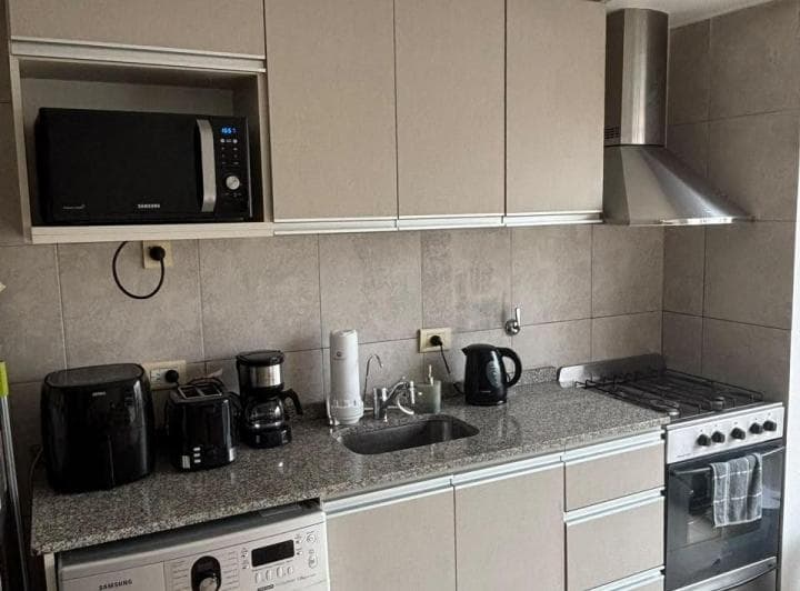 Cocina equipada con mesada de granito, bacha, anafe, microondas y campana extractora.
