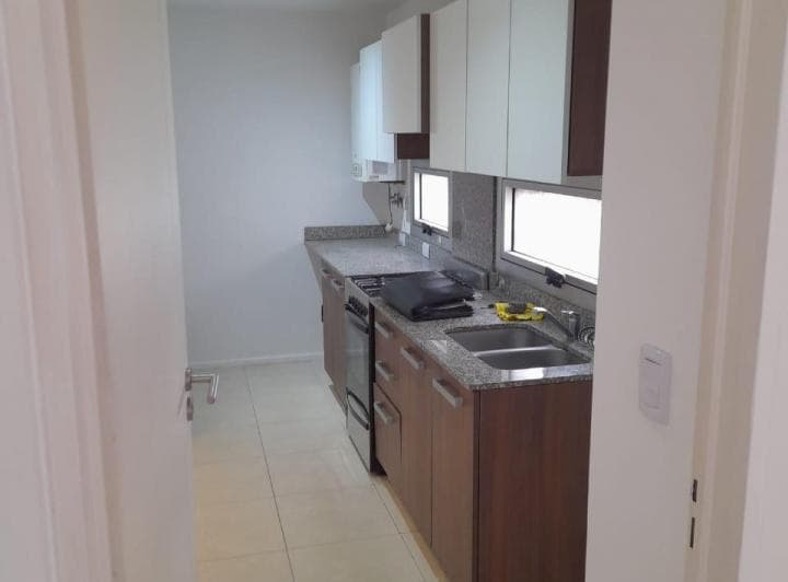 Cocina con mesada de granito, bacha doble, anafe y alacenas de madera.