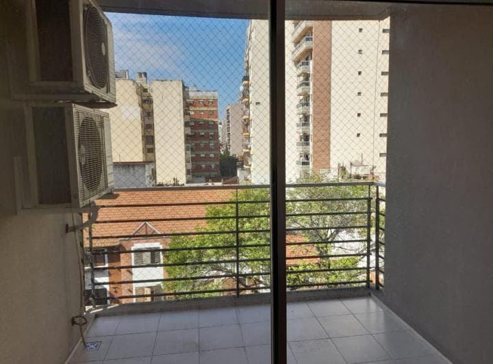 Balcón con baranda metálica, piso de cerámica y vista a la ciudad.