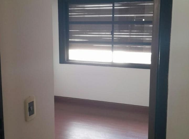 Dormitorio vacío con ventana y persiana, piso de madera.