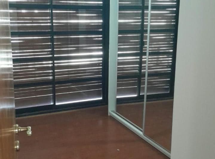Dormitorio con ventanal, persianas y amplio placard espejado.