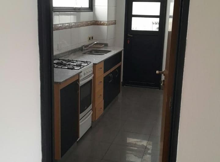 Cocina con mesada, anafe, horno y puerta de acceso al exterior.