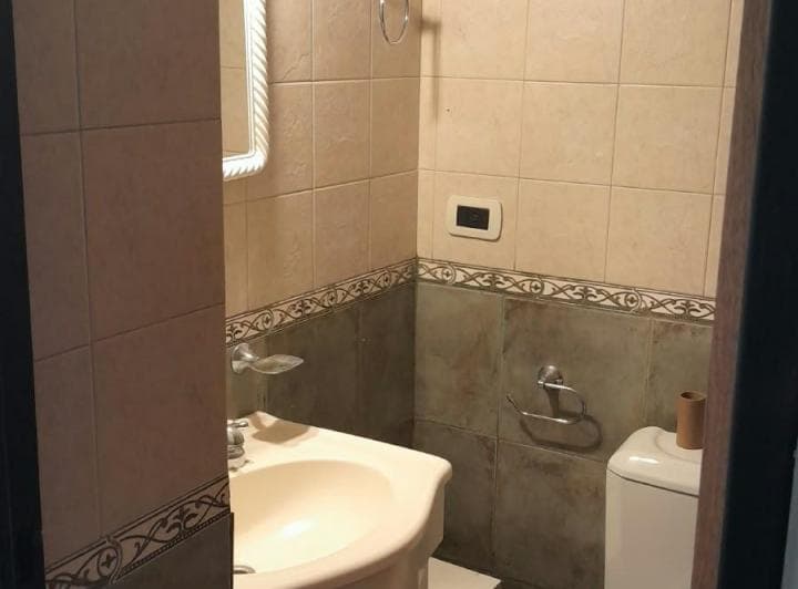 Toilette con inodoro, lavatorio y espejo, azulejos decorados.