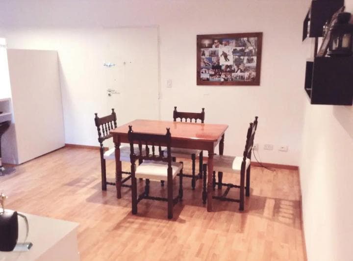 Comedor con mesa de madera y sillas en ambiente con piso de parquet.