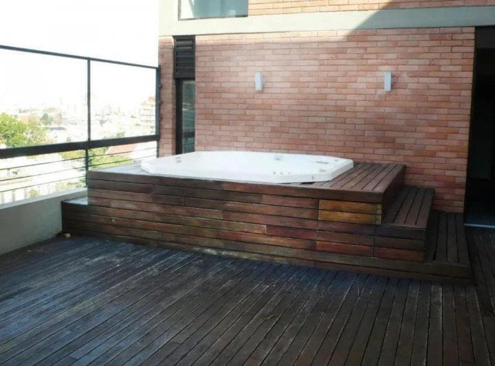 Jacuzzi exterior en deck de madera con vista panorámica de la ciudad.
