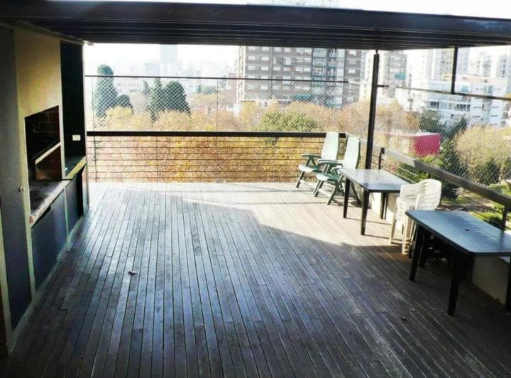 Amplia terraza con parrilla, mesas, sillas y vista urbana.