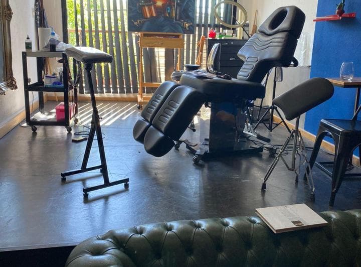 Living con silla de tatuar, sillón de cuero y ventana con rejas.
