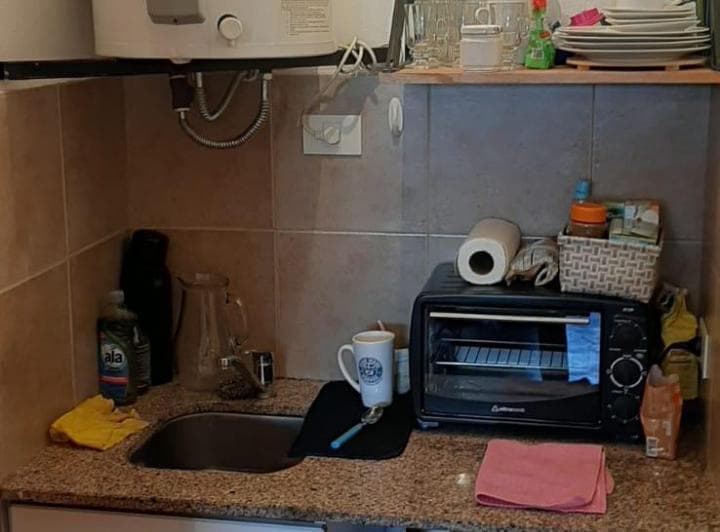 Cocina pequeña con mesada, bacha, tostadora eléctrica y calentador de agua.