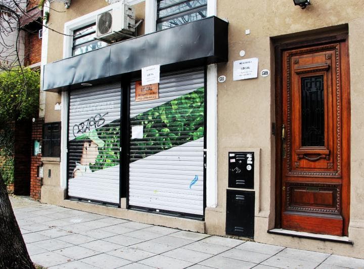 Fachada de un edificio con puerta de madera y persianas metálicas.