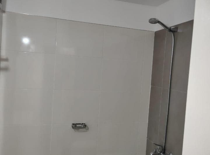 Ducha con azulejos blancos y grises, y jabonera.