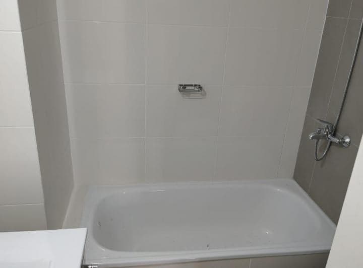 Bañera blanca con azulejos y grifo en baño.
