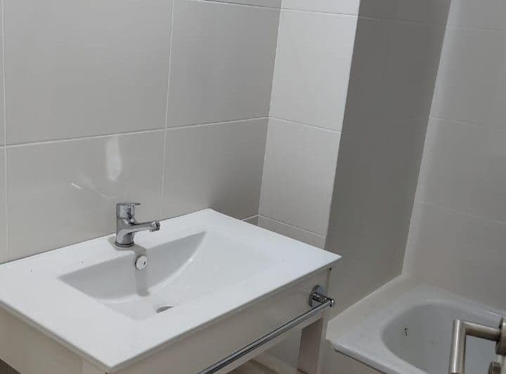 Lavatorio con grifo y mueble, junto a bañera.