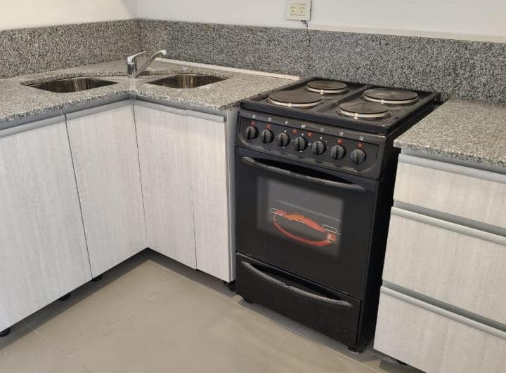 Cocina con anafe, horno negro y mesada de granito.
