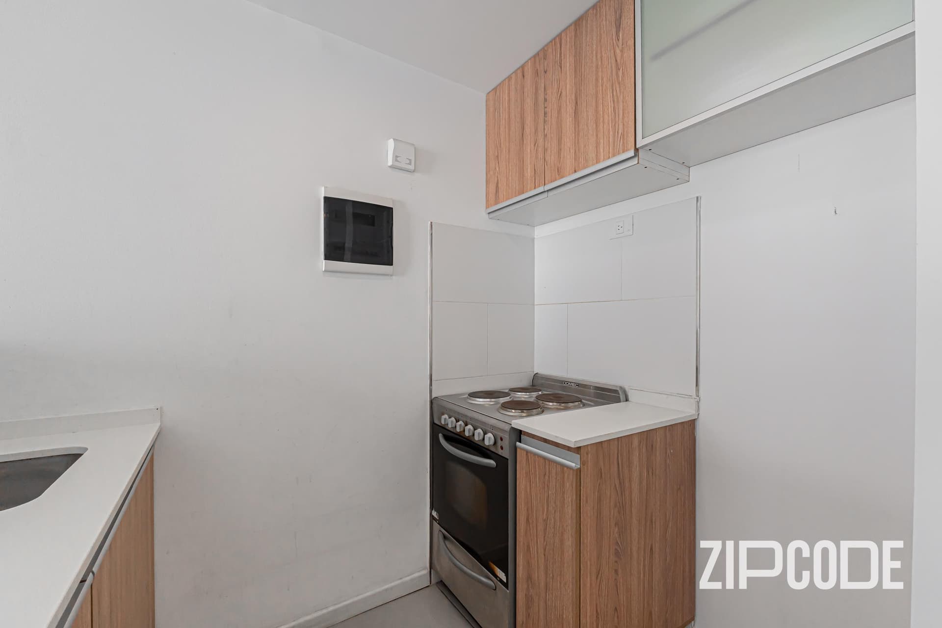 Cocina con anafe, horno, mesada y alacenas de madera y vidrio.