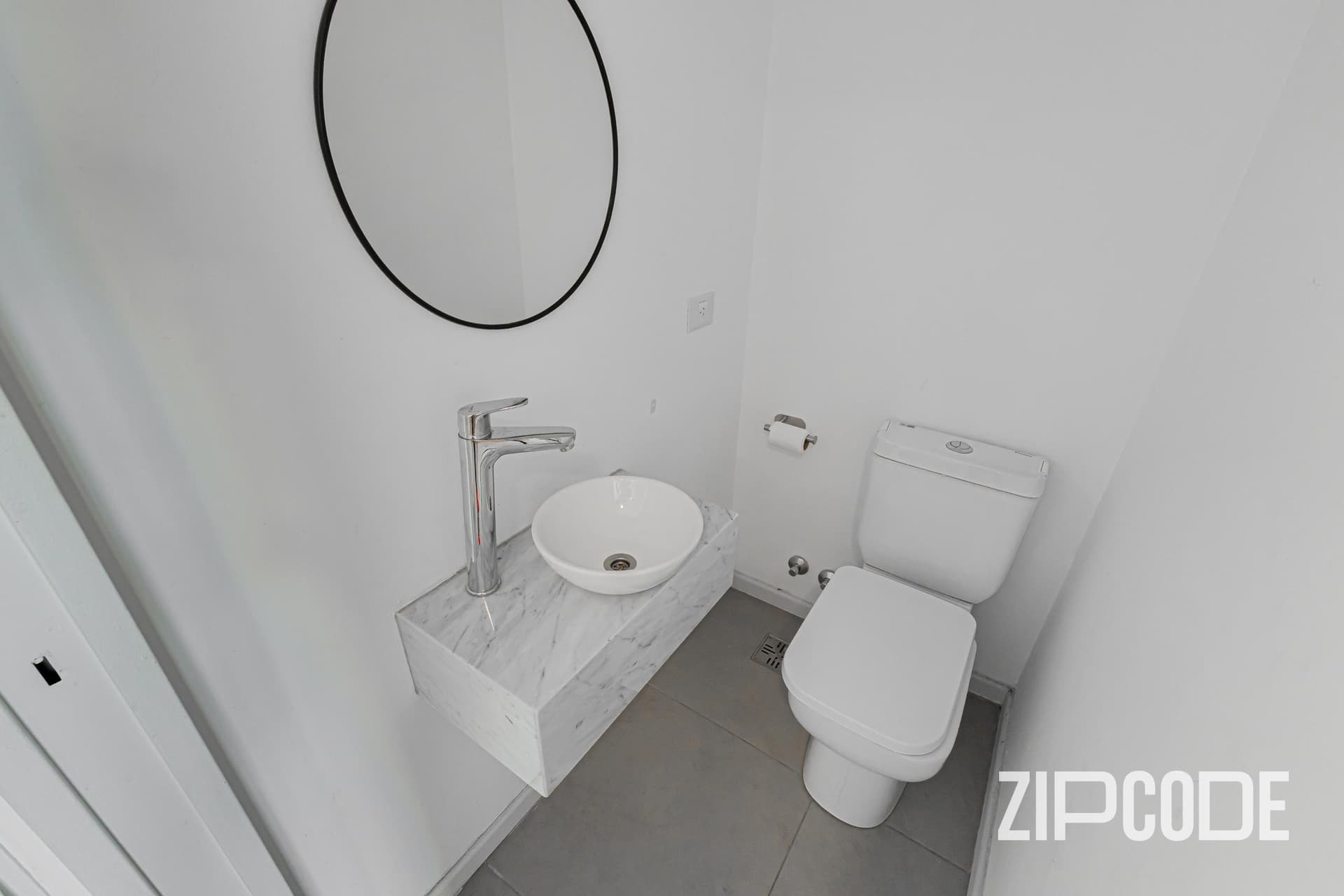 Toilette con inodoro, lavatorio de bacha sobre mesada de mármol.