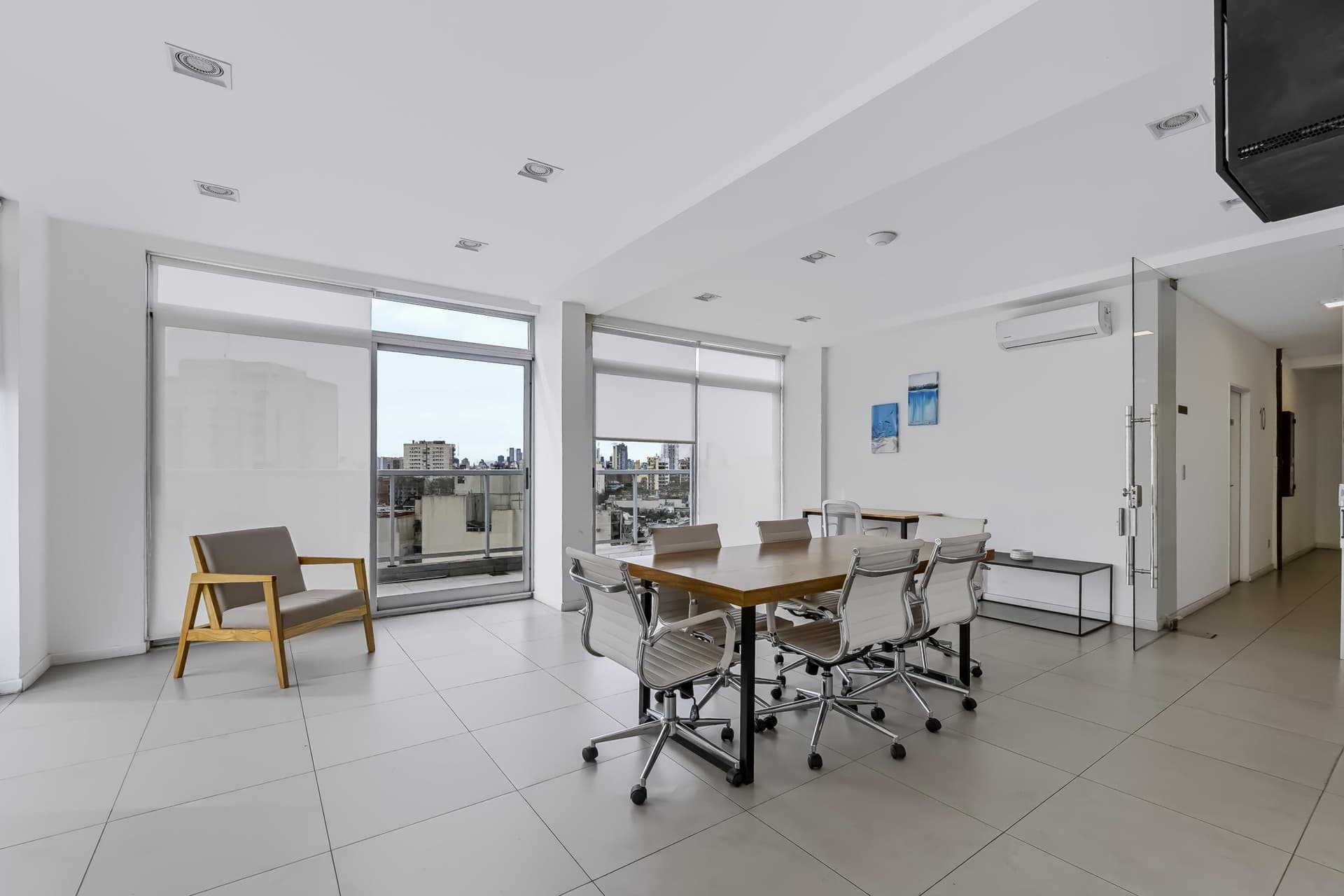 SUM con mesa de reuniones, sillas y sillón con vista exterior.