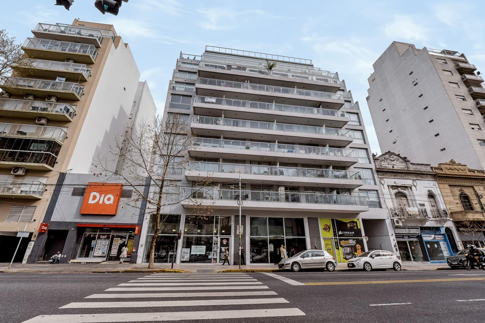 Fachada del edificio con balcones de vidrio y negocios en planta baja.