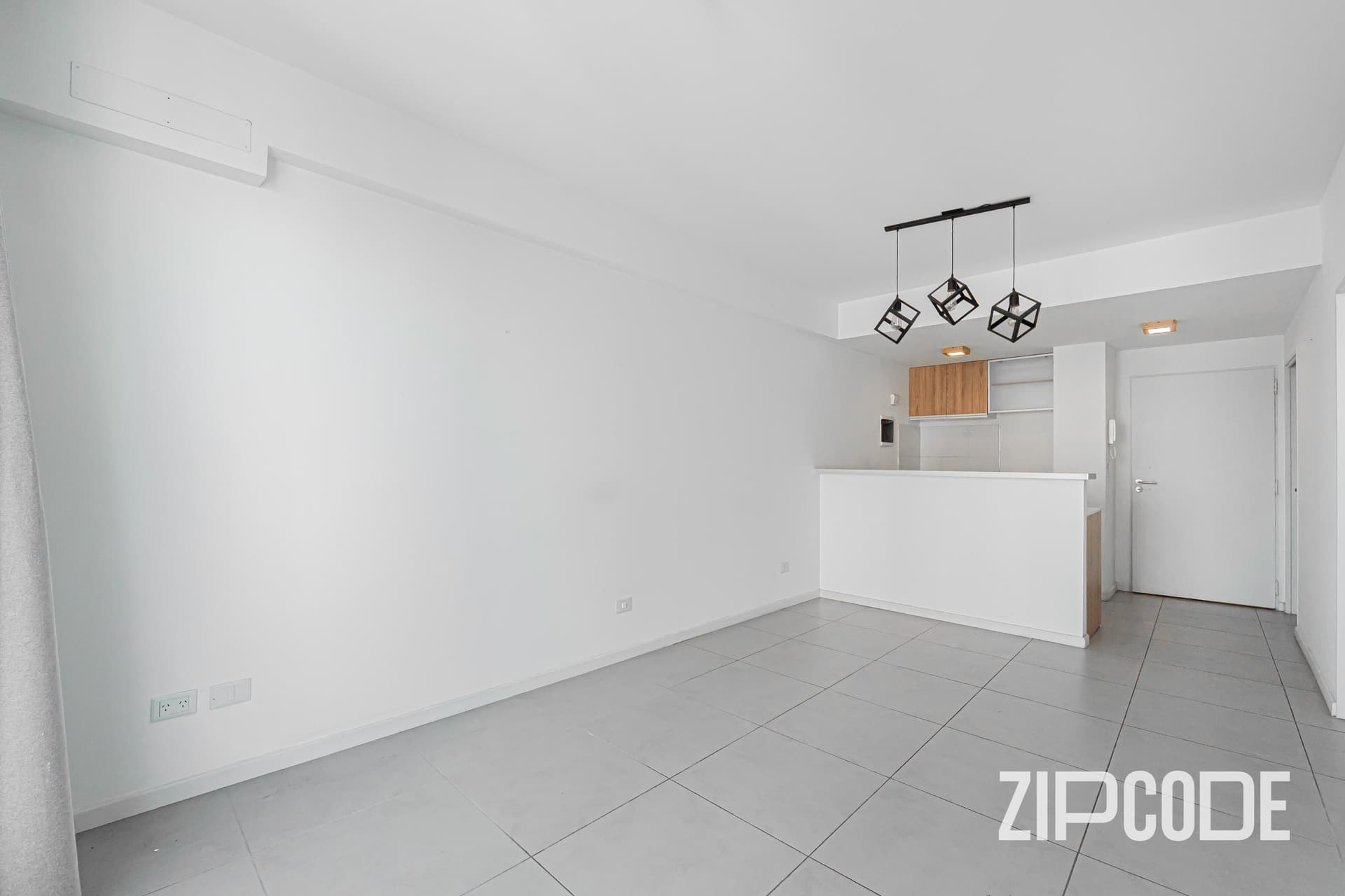 Living comedor vacío con aire acondicionado y vista a la barra de cocina.