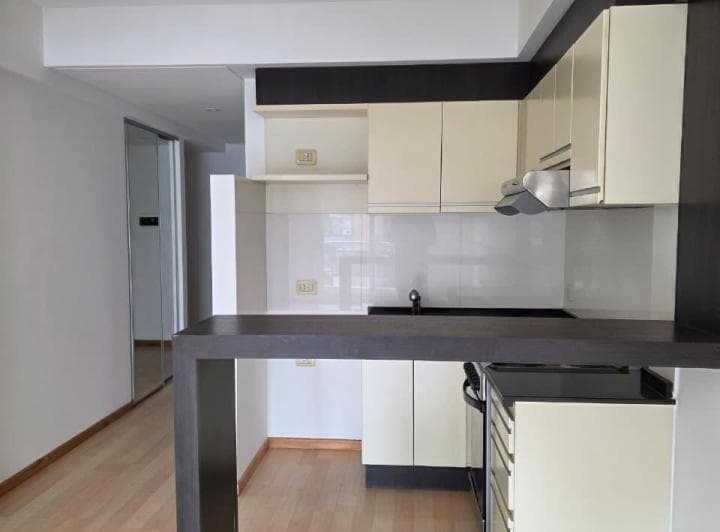 Cocina integrada con barra, alacenas color crema y detalles oscuros.