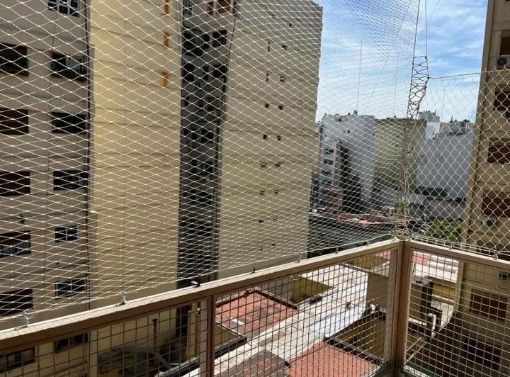 Balcón con rejas de seguridad y vista a edificios altos en un día soleado.