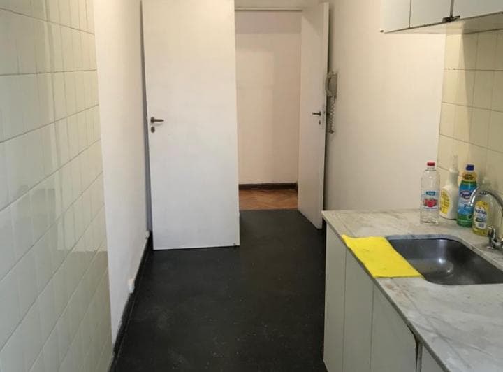Cocina con mesada, bacha, alacenas superiores y puertas blancas al fondo.
