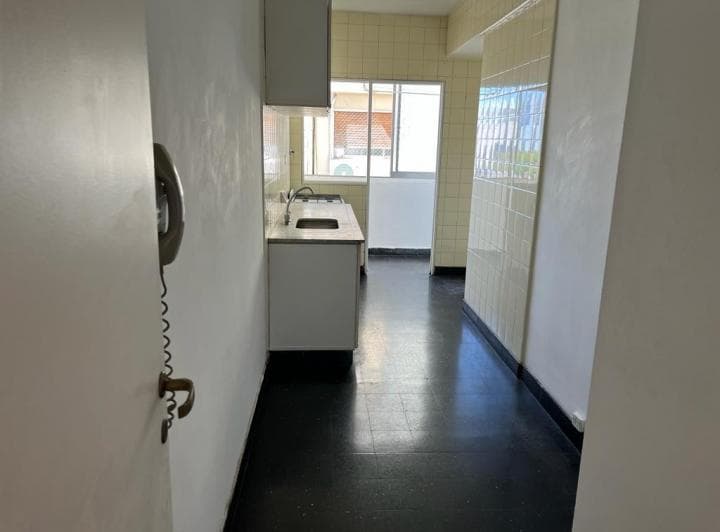 Cocina con mesada, bacha, anafe, azulejos y un teléfono antiguo en la pared.