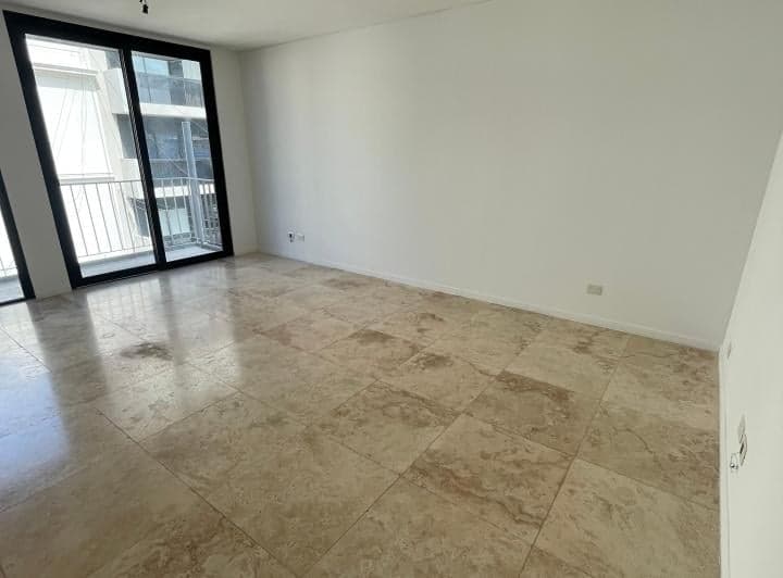 Dormitorio vacío con ventanal, piso de mármol, paredes blancas y vista exterior.