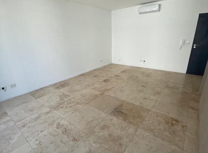 Dormitorio vacío con aire acondicionado, paredes blancas y piso de mármol.