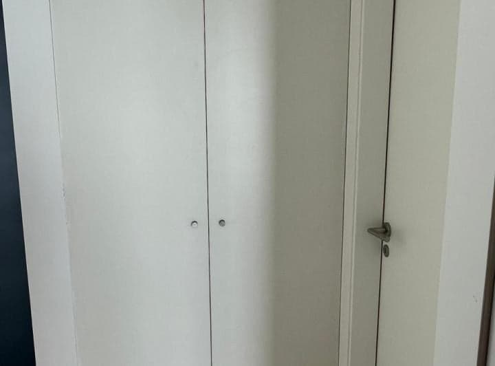 Dormitorio con placard empotrado blanco y puerta de madera clara.