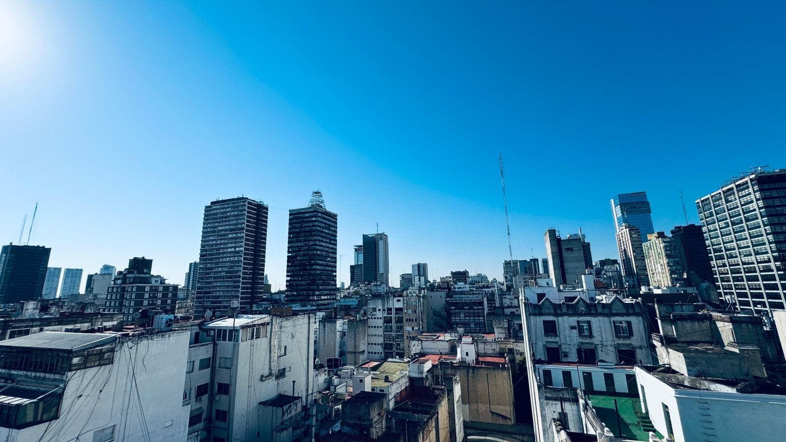 Vista: panorámica de la ciudad con edificios altos y cielo azul.
